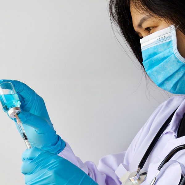 Doctor or scientist hand in blue nitrile gloves holding flu ,measles, coronavirus, vaccine shot